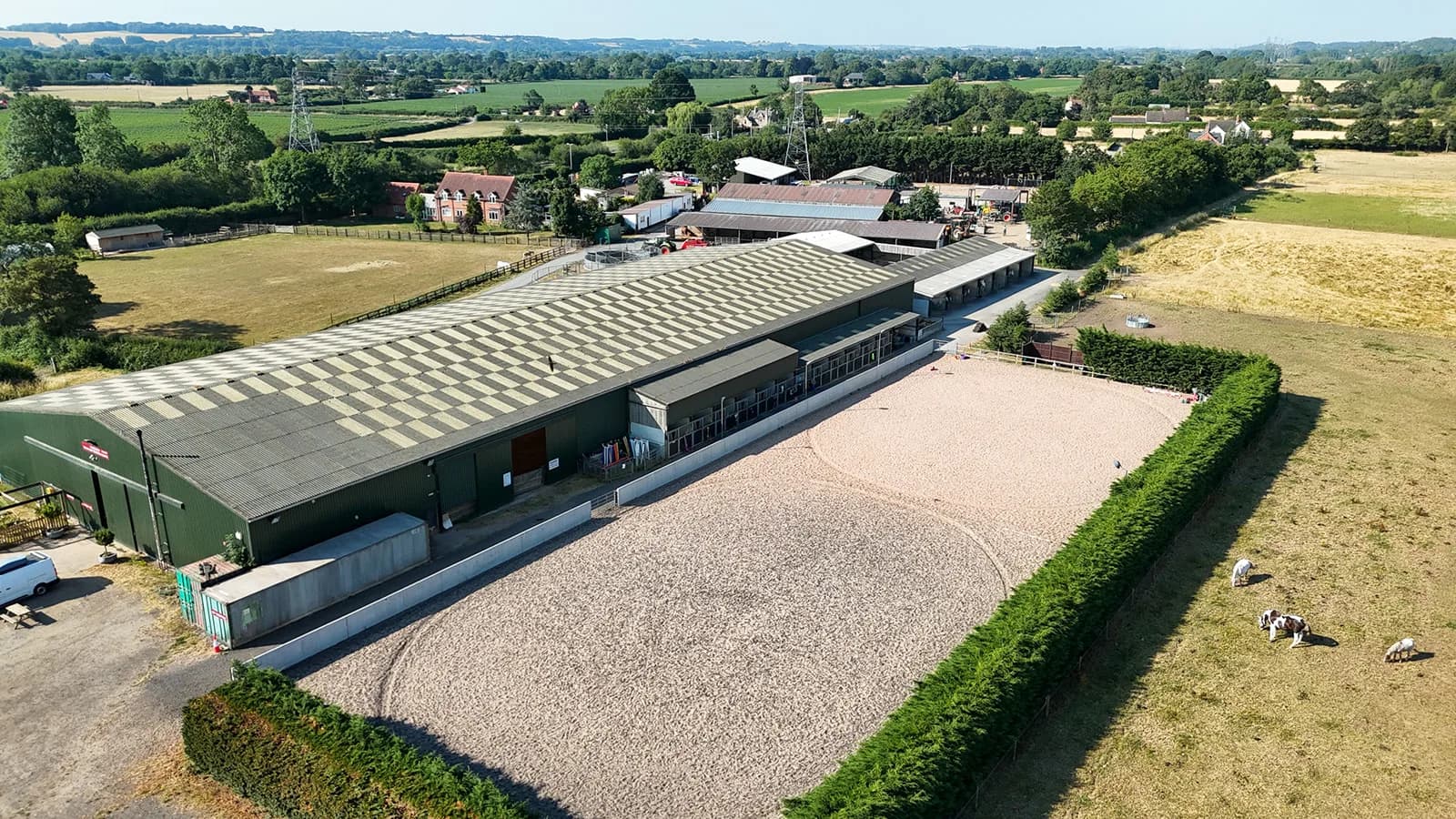 Aerial view of the outdoor sand arena at Trentvalley Equestrian Centre with the indoor arena building and Nottinghamshire countryside beyond