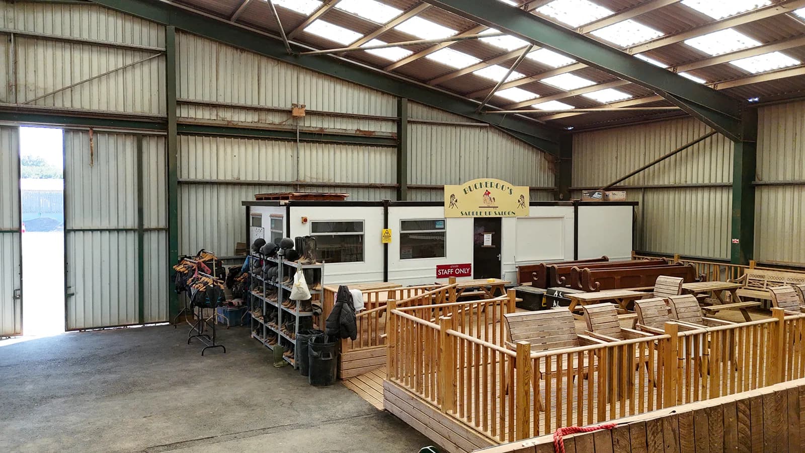 Interior of the indoor arena at Trentvalley Equestrian Centre showing the reception office and wooden viewing gallery